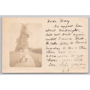 May include: Sepia-toned vintage postcard featuring a windmill and two figures on a path. The postcard includes handwritten text, likely a personal message. The image evokes a sense of nostalgia and historical charm.