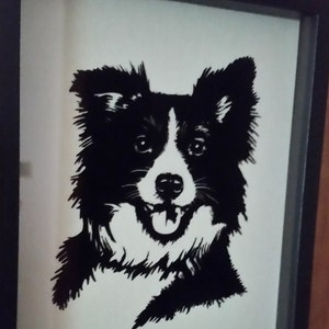 May include: Black and white silhouette of a Border Collie dog with its tongue sticking out, framed in a black frame.
