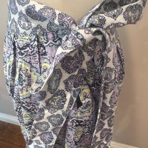 K&ouml;nnte beinhalten: Wickelrock mit Paisley-Muster in Wei&szlig;, Lavendel, Gelb und Schwarz. Der Rock wird mit einem passenden Stoffg&uuml;rtel in der Taille gebunden, wodurch ein geschichteter Effekt entsteht. Der Stoff wirkt weich und flie&szlig;end.