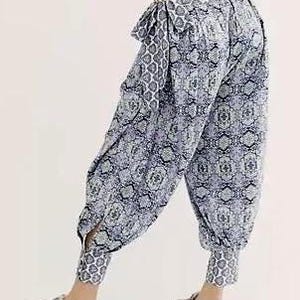 K&ouml;nnte beinhalten: Haremshose mit blau-wei&szlig;em Muster, geraffter Taille und Kn&ouml;chelb&uuml;ndchen. Die Hose hat eine lockere Passform und eine dekorative Schleife. Der Stoff weist ein sich wiederholendes geometrisches Design auf. Die Hose ist ca. 100 cm lang.