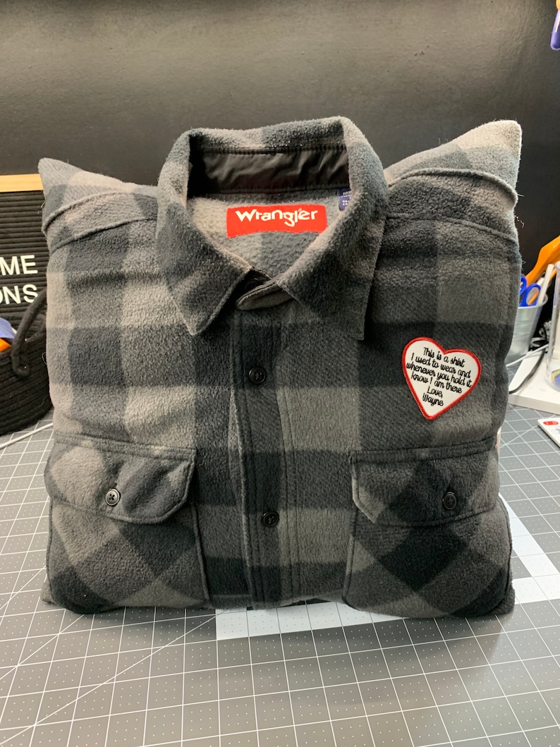 May include: A gray and black plaid flannel shirt pillow with a red heart-shaped patch that says "This is a shirt I want to wear and whenever you hold it know I am there. Love, Wayne."
