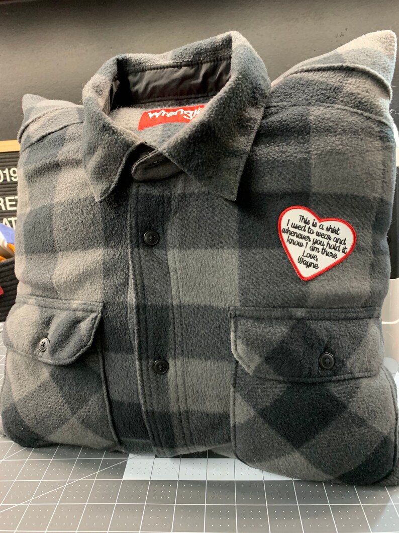 May include: A gray and black plaid flannel shirt with a heart-shaped patch that says "This is a shirt I used to wear and whenever you hold it know I am there Love Wayne".
