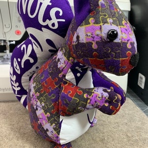May include: Purple and white plush squirrel toy with a jigsaw puzzle pattern and the word "Nuts" on the back.
