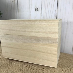 May include: A plain wooden box with a hinged lid. The box is made of light-colored wood and has a natural finish.