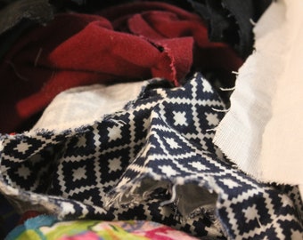 May include: A pile of fabric scraps in various colors and patterns, including black, red, white, and blue. The fabric scraps are arranged in a random order, creating a textured and colorful composition.