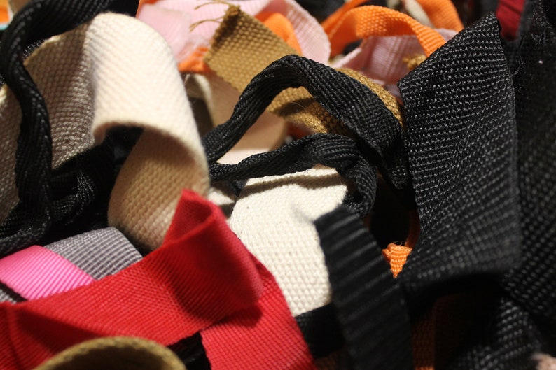 May include: A close-up of a variety of woven and braided straps in different colors, including black, white, brown, red, orange, and pink.
