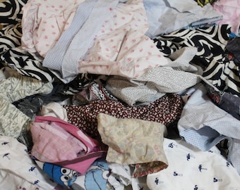 May include: A pile of colorful fabric scraps in various patterns and textures, including floral, polka dot, and striped designs. The fabric scraps are a mix of cotton and other materials.