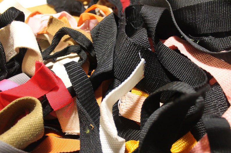 May include: A pile of colorful fabric ribbon scraps in various widths and textures, including black, white, red, orange, pink, and brown.