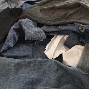 May include: A pile of blue denim fabric scraps, some with frayed edges, and a few pieces of white and brown fabric.