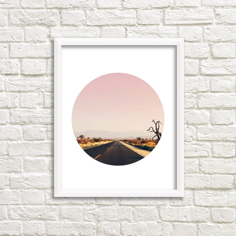Puede incluir: Una impresi&oacute;n enmarcada de una fotograf&iacute;a circular que muestra un camino del desierto que conduce a la distancia bajo un cielo rosado.