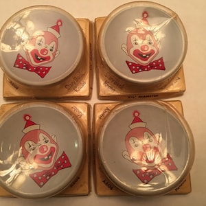 May include: Four vintage Story Book Knobs with a clown face design. Each knob is 3 1/2 inches in diameter and is packaged in a clear plastic wrapper.