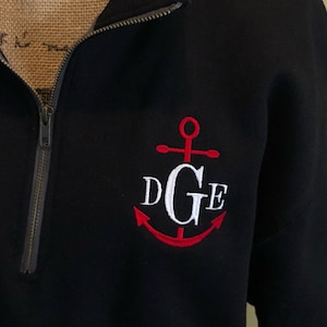 May include: Black quarter-zip sweatshirt with a red anchor and white embroidered initials "DGE".