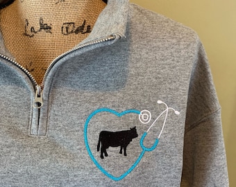 May include: Gray sweatshirt with a blue embroidered heart and stethoscope, with a black silhouette of a cow inside the heart.