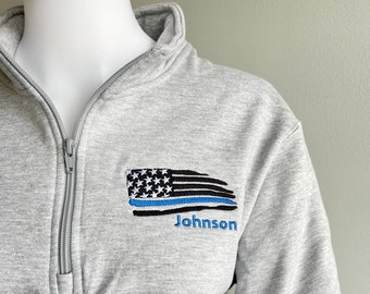 May include: A gray 1/4 zip sweatshirt with a blue line American flag and the name "Johnson" embroidered on the front.