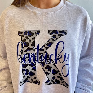 May include: Gray sweatshirt with a large black and blue leopard print letter K and the word "kentucky" in blue cursive writing.