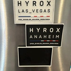 May include: Three rectangular patches arranged vertically. The top patch is white with black text reading HYROX LAS_VEGAS and PRO_DOUBLES_SEASON_2025/2026. The middle patch is black with white text reading HYROX ANAHEIM and OPEN_SINGLES_SEASON_2025/2026.