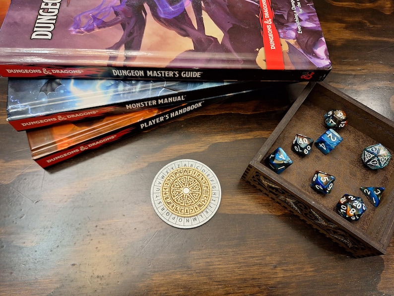 May include: A tabletop gaming scene featuring Dungeons & Dragons books: Dungeon Master's Guide, Monster Manual, and Player's Handbook. A wooden dice tray holds various multi-sided dice. A circular game piece with a cipher design is also present.