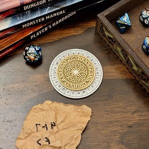 May include: A tabletop gaming scene featuring a wooden box with dice, a circular cipher, a 20-sided die, and a crumpled paper with symbols. Books with "Dungeons & Dragons" and "Monster Manual" are in the background. The cipher is gold and white.