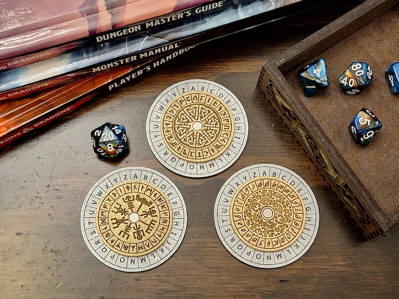 May include: Three round, light-colored coasters with a gold-colored, circular design and an outer ring of letters. A wooden box with dice and a stack of books are also visible. The dice are blue, black, and white.