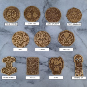 Puede incluir: Una colecci&oacute;n de once recortes de madera con varios dise&ntilde;os, incluyendo una br&uacute;jula vikinga, un &aacute;rbol celta, un calendario azteca, un dobl&oacute;n pirata, un laberinto, Cthulhu, un pulpo, el martillo de Thor, un &iacute;dolo Tiki, una calavera y la llave de Goonies. Color marr&oacute;n claro.