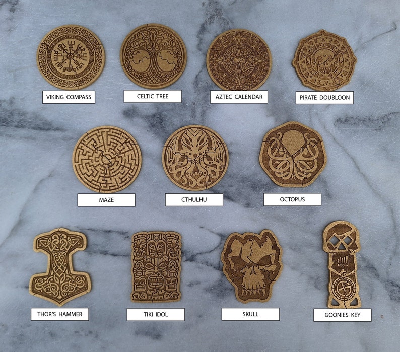 Puede incluir: Una colecci&oacute;n de once recortes de madera con varios dise&ntilde;os, incluyendo una br&uacute;jula vikinga, un &aacute;rbol celta, un calendario azteca, un dobl&oacute;n pirata, un laberinto, Cthulhu, un pulpo, el martillo de Thor, un &iacute;dolo Tiki, una calavera y la llave de Goonies. Color marr&oacute;n claro.