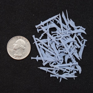 May include: A pile of small, white plastic swords, about the size of a quarter. The swords are all different shapes and sizes, and some have intricate details.
