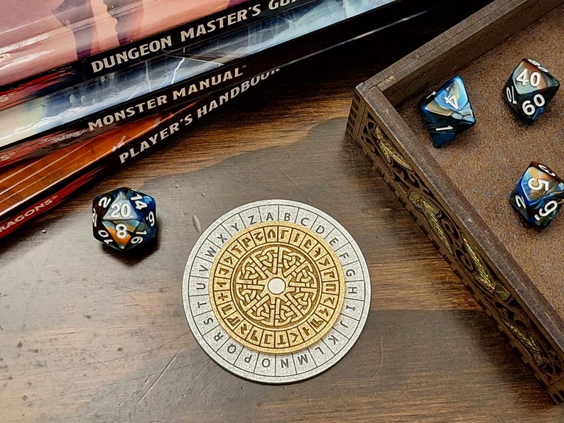 May include: A wooden dice tray with several multi-sided dice, a circular wooden cipher, and a stack of role-playing game books. The dice are various colors, including blue, black, and gold. The cipher has a central design and an outer ring of letters.