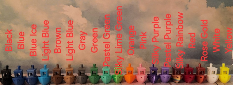 Puede incluir: Una fila de 20 peque&ntilde;os barcos de juguete coloridos, cada uno con un color y dise&ntilde;o diferente. Los barcos est&aacute;n dispuestos en una l&iacute;nea de izquierda a derecha, con los colores negro, azul, azul hielo, azul claro, marr&oacute;n, azul claro, gris, verde, verde pastel, verde lima, naranja, rosa, morado sedoso, morado pastel, arco&iacute;ris, rojo, oro rosa, blanco y amarillo.