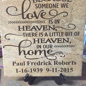May include: A brown and beige stone plaque with a black inscription that reads "Because someone we love is in heaven, there is a little bit of heaven in our home." The plaque also includes the name "Paul Fredrick Roberts" and the dates "1-16-1939 9-11-2015".