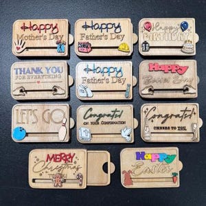 May include: A collection of wooden gift tags with various celebratory messages, including "Happy Mother's Day," "Happy Father's Day," and "Happy Birthday." Each tag features colorful accents and small decorative elements.