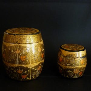 Peut inclure: Deux boîtes rondes décoratives avec des motifs floraux complexes. La plus grande boîte est dorée avec des accents noirs, tandis que la plus petite boîte est noire avec des accents dorés.