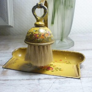 Peut inclure: Un ensemble vintage de ramasse-poussière et de brosse jaunes. La brosse a un dessus en forme de dôme avec des motifs floraux et une poignée en boucle. La pelle et la brosse sont jaunes avec des accents floraux. Les poils de la brosse sont brun clair.