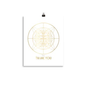 Puede incluir: Un póster blanco con un diseño geométrico dorado y las palabras "THANK YOU" en dorado. El póster está sujeto con un clip negro.