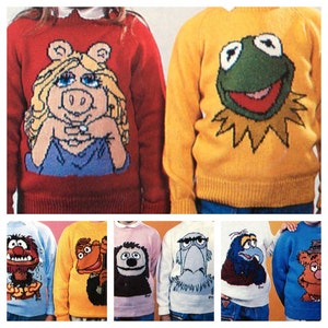 May include: A collection of children's sweaters featuring Muppets characters. The sweaters are in various colors, including red, yellow, blue, and pink. Each sweater has a different Muppet character design, such as Miss Piggy, Kermit the Frog, and Fozzie Bear.
