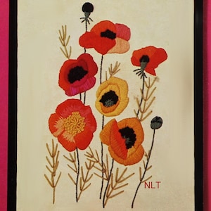 May include: Embroidered artwork featuring vibrant red, orange, and yellow poppies with black centers. The flowers are set against a cream-colored background, with brown stems and leaves. The artwork is framed in a black frame.