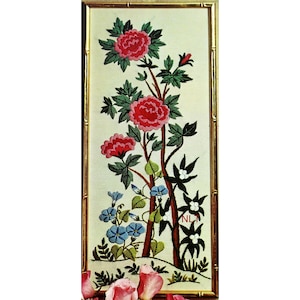 May include: Embroidered floral artwork in a gold bamboo-style frame. The artwork features red peonies, green leaves, blue morning glories, and white flowers. The background is a cream color. The artwork is rectangular and has the initials "NLM" in the lower right corner.