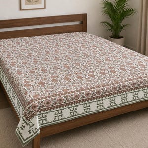 May include: A rectangular bed sheet featuring a white base with a repeating floral pattern in muted brown and green tones. The border displays a distinct geometric motif in dark green, framing the central floral design across the entire surface.