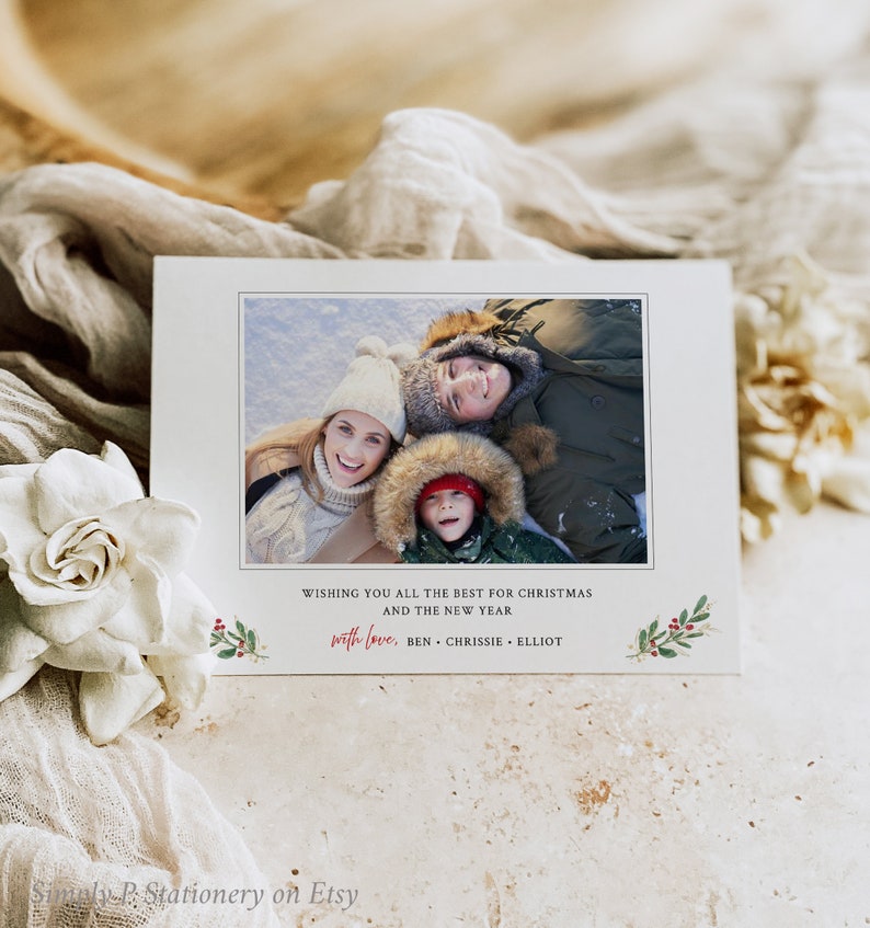 May include: A white Christmas card featuring a family photograph and the message "Wishing you all the best for Christmas and the New Year, with love, Ben, Chrissie, Elliot." Decorated with festive green and red accents.
