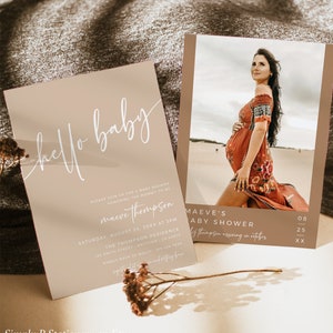 May include: A beige baby shower invitation with a white script font that says "hello baby". The invitation includes the name "Maeve Thompson" and details for the shower, which is scheduled for August 25th at 3pm. The invitation also includes a RSVP number.