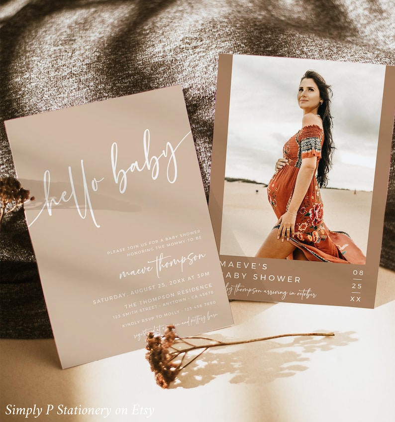 May include: A beige baby shower invitation with a white script font that says "hello baby". The invitation includes the name "Maeve Thompson" and details for the shower, which is scheduled for August 25th at 3pm. The invitation also includes a RSVP number.