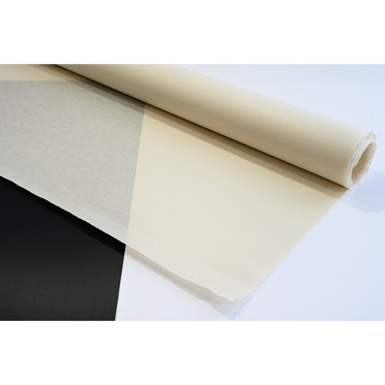 May include: A roll of white canvas fabric, partially unrolled, revealing the smooth, textured surface. The canvas is rolled up on a black surface.