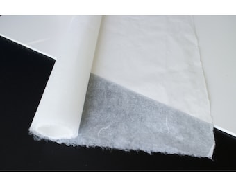 Könnte beinhalten: Eine Rolle weißes, strukturiertes Papier. Das Papier ist abgewickelt, um die strukturierte Oberfläche zu zeigen.