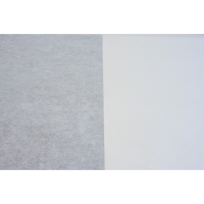 May include: A close-up of two pieces of fabric. The fabric on the left is a light gray, textured material. The fabric on the right is a smooth, white material.