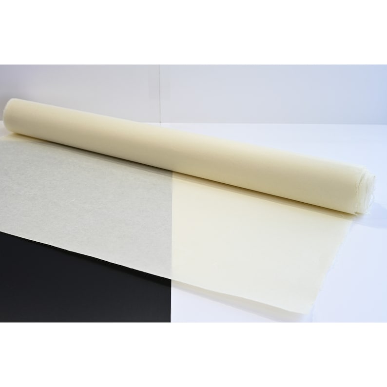 May include: A roll of white, unbleached, natural paper. The paper is rolled up and partially unrolled, showing the texture of the paper.