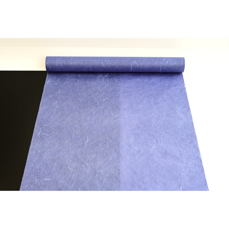 K&ouml;nnte beinhalten: Eine Rolle blaues Seidenpapier mit einer strukturierten, faserigen Oberfl&auml;che. Das Papier ist aufgerollt und teilweise abgewickelt, wodurch die blaue Farbe und die Textur sichtbar werden.