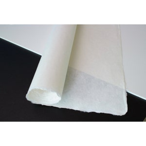 May include: A roll of white, textured paper with a slightly rough surface. The paper is rolled up and partially unrolled, revealing the texture of the paper.