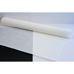 May include: A roll of white tissue paper, unrolled on a white surface with a black background.