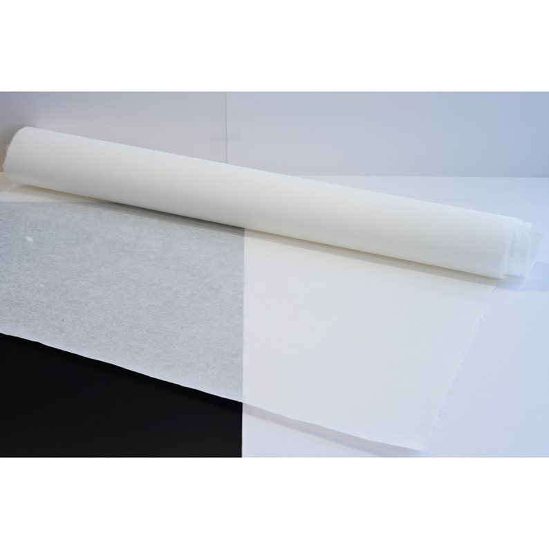 May include: A roll of white tissue paper, unrolled on a white surface with a black background.