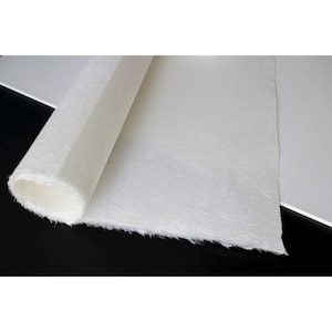Puede incluir: Un rollo de papel blanco texturizado con un borde ligeramente rugoso. El papel está desenrollado y parcialmente enrollado, revelando el interior blanco.