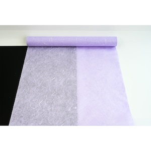 K&ouml;nnte beinhalten: Eine Rolle helllila Seidenpapier mit einer strukturierten, zerknitterten Oberfl&auml;che. Das Papier ist teilweise abgewickelt und zeigt eine wei&szlig;e Seite.